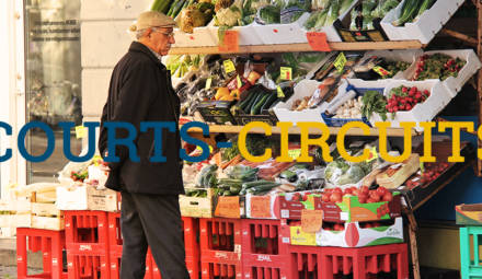 vieil homme devant un étal de fruits et légumes