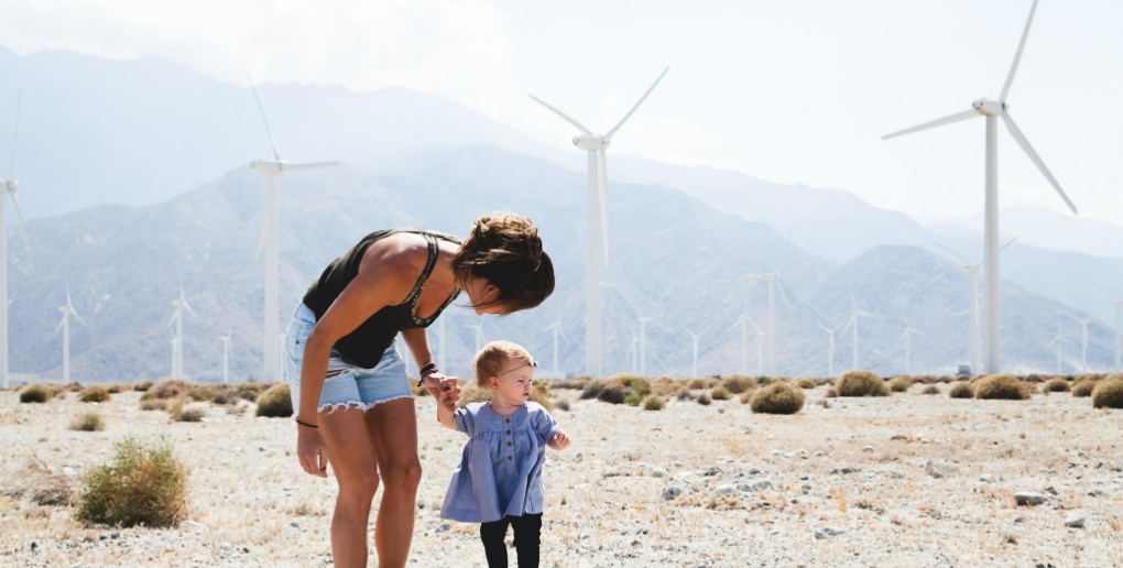 Une femme et un enfant près d'un champ d'éoliennes. 