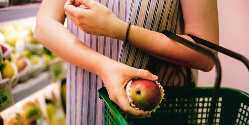 une femme met une pomme dans un panier à courses