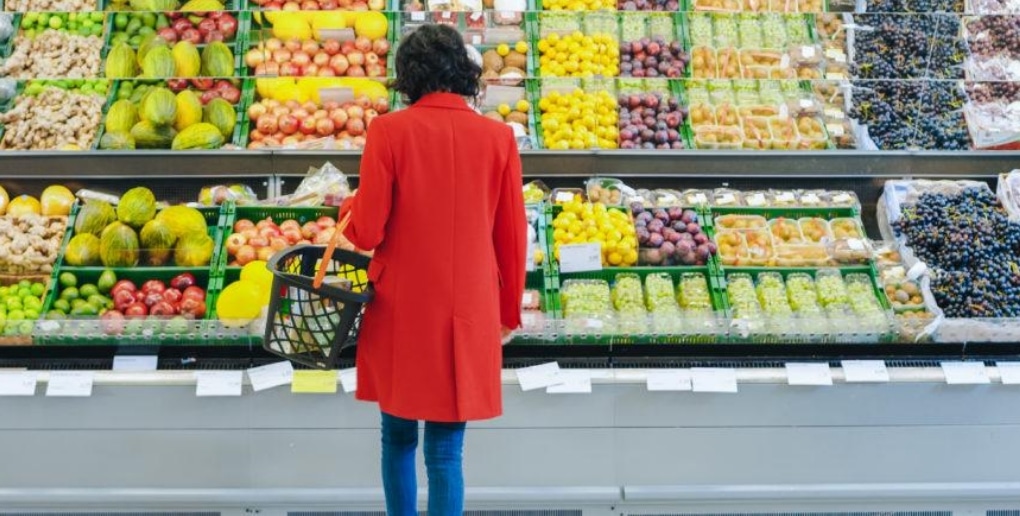 femme devant un rayon de fruits dans un supermarché